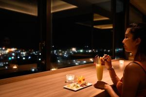 a woman sitting at a table with a drink at Art Hotel Ishigakijima in Ishigaki Island