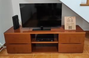 a flat screen tv on a wooden entertainment center at A Casa da Loja in Lagoa