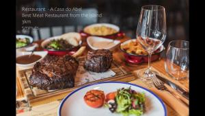 a table with a plate of food and a glass of wine at A Casa da Loja in Lagoa