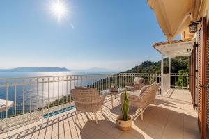 a balcony with chairs and a table and the ocean at Aigaio pool Villa, gaze the sunset over the Aegean sea in Glóssa +60 photos