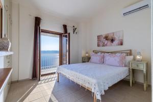 a bedroom with a bed and a large window at Aigaio pool Villa, gaze the sunset over the Aegean sea in Glóssa