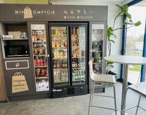 a store with two refrigerators and a table and chairs at Kyriad Toulouse Sud - Roques in Roques Sur Garonne