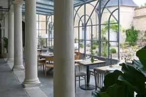 a restaurant with tables and chairs and large windows at Hôtel les Prés in Saint-Hilaire-le-Châtel
