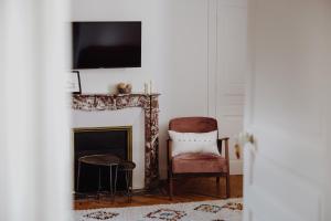 Una sala de estar con una silla y una chimenea. en Domaine de Millon, en Soustons