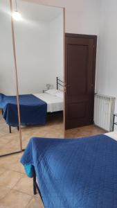 a room with two beds and a door and a mirror at Stanza in Villa in Torvaianica