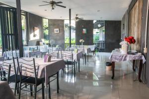 a dining room with tables and chairs with flowers on them at Judy Park & Resort Buriram in Buriram