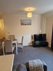 een woonkamer met een tv en een tafel en stoelen bij Hereford - Mayflower Coach House, Modern 2 Bedroom Property With Parking, Located South Of Hereford City, Suitable For Small Family, Couple Or Contractors - Sleeps Up To 5 Guests - Hosted by RENTMYHOUSE in Hereford