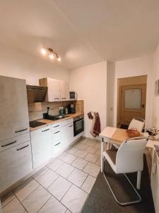 a kitchen with white cabinets and a table and chairs at Ferienwohnung zum Schreckenberg in Annaberg-Buchholz