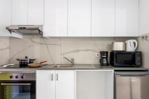 kuchnia z białymi szafkami, zlewem i kuchenką mikrofalową w obiekcie Sunstone - Cozy Studio W Terrace in Larnaca w Larnace