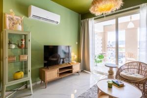salon z zielonymi ścianami i telewizorem w obiekcie Sunstone - Cozy Studio W Terrace in Larnaca w Larnace +8 zdjęć