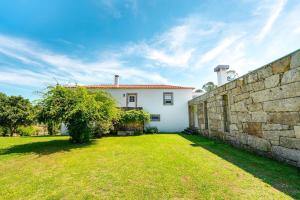 a white house with a stone wall and a yard at Portugal Active Oliveiras Farm in Viana do Castelo