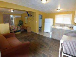 a living room with yellow walls and a kitchen and a couch at Sands Motel in St. George