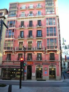 un edificio rosa en una calle de la ciudad con un semáforo en Hostal Sonia Granada, en Granada