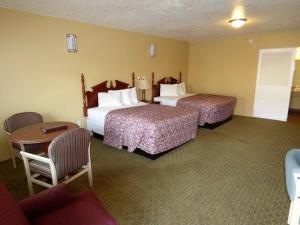 a hotel room with two beds and a table and chairs at Economy Inn & Suites in St. George