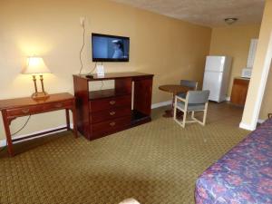 a hotel room with a bed and a dresser with a television at Economy Inn & Suites in St. George