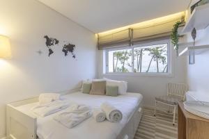 a white room with a bed with towels on it at Tide Terrace Duplex by Portugal Active in Viana do Castelo