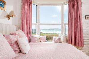 ein Schlafzimmer mit einem rosa Bett mit einem großen Fenster in der Unterkunft Beautiful family house with amazing sea views in Padstow