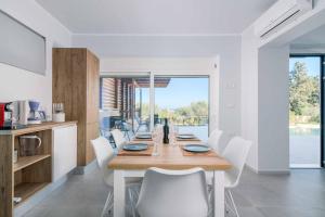 a dining room with a wooden table and white chairs at Villa Anastazia in Koskinou