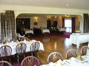 uma sala de jantar com mesas e cadeiras brancas em Wheyrigg Hall Hotel em Wheyrigg