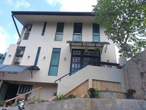 a white building with a staircase in front of it at Infinity Boutique Hotel Kata Beach in Ban Kata