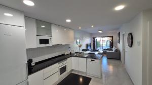 a kitchen with white cabinets and a living room at Casa Arona in San Juan de los Terreros
