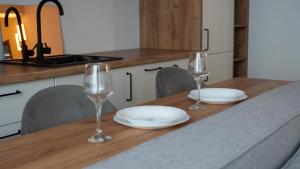 a table with two wine glasses and plates on it at Cozy Apartments - Ared UTA Flat in Arad +27 photos