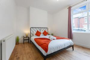 a bedroom with a bed with orange pillows and a window at Modern High Spec House, Free Parking, 4 bed, sleeps 7 in Shield Row