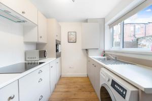 a kitchen with white cabinets and a window at Modern High Spec House, Free Parking, 4 bed, sleeps 7 in Shield Row