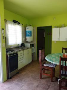 eine Küche mit grünen Wänden, einem Tisch und einem Herd in der Unterkunft Quetrihue Mar de las Pampas in Mar de las Pampas