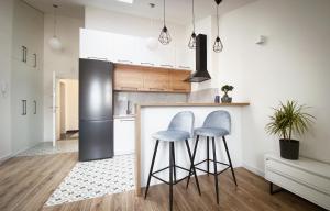 a kitchen with two bar stools and a refrigerator at Apartament w centrum Rzeszowa - Grodzisko in Rzeszów +20 photos