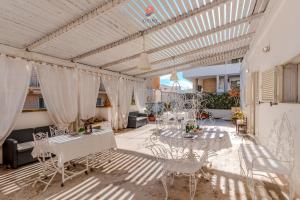 a patio with white tables and chairs and curtains at Palazzo Grassi by Vivimy in Gallipoli