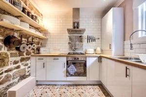 a kitchen with white cabinets and a stone wall at West End Holiday Homes in Glasgow