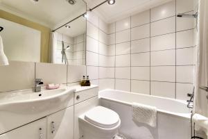 a white bathroom with a tub and a toilet and a sink at West End Holiday Homes in Glasgow