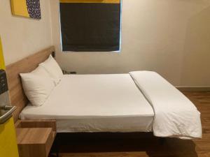 a bed with white sheets in a room at Hotel I-stay Hitec in Hyderabad