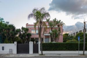 a pink building with palm trees in front of it at Villa Olimpia in Mondello