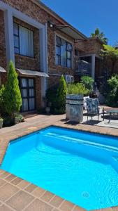 a blue swimming pool in front of a house at Dormio Manor Guest Lodge in Secunda