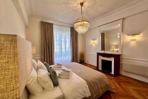 Un dormitorio con una cama con chimenea y una lámpara de araña. en QUAI PROMENADE VIEW Balcony with breathtaking view, en Niza