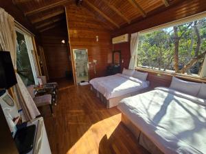 una camera da letto con due letti e una grande finestra di Nanzhuang Haoshanhaishui B&B a Hung-mao-kuan