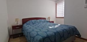 a bedroom with a bed with a blue comforter and a window at Rincón Puyehue Primer Nivel in Puyehue