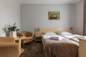 a hotel room with two beds and a chair at Domus Hotel in Birštonas