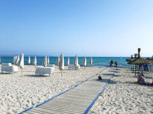 a beach with white umbrellas and chairs and the ocean at Bonito apartamento delante del mar in Can Pastilla