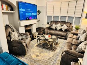 ein Wohnzimmer mit Sofas und einem Flachbildfernseher in der Unterkunft Elegant 4BR Home: Stylish Comfort Retreat in Derwent Haugh