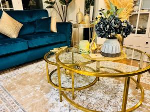 ein Wohnzimmer mit einem Glastisch und einem blauen Sofa in der Unterkunft Elegant 4BR Home: Stylish Comfort Retreat in Derwent Haugh + 33 Fotos