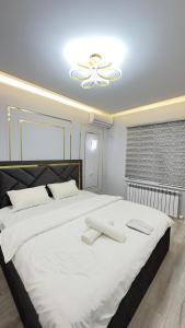 a bedroom with a large white bed with a ceiling at Turkistan apart Hotel ближе Караван сарая in Türkistan