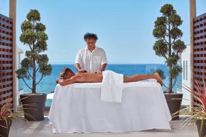 a man laying on a massage table with a man on it at Icon Suites by the sea in Potos