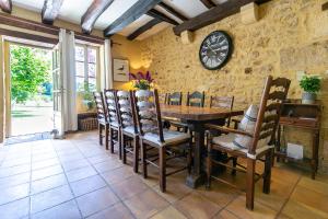 una sala da pranzo con tavolo, sedie e orologio di La Maison Louverie a Pontours