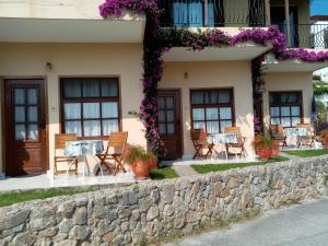 a building with chairs and tables in front of it at Dawn's Rooms in Patitiri