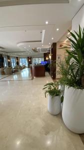 リヤドにあるسمت ان النرجس للشقق المخدومة - Samt Inn Al Narjis Serviced Apartmentsの白い大きな鍋2つ(植物付)が備わるロビー