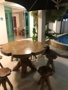 einen großen Holztisch und Stühle mit Sonnenschirm in der Unterkunft Praia do Flamengo 150m da praia Casa Ballalai in Salvador