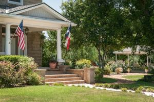 Due bandiere americane sul davanti di una casa di Sandstone Street Bed and Breakfast a Llano